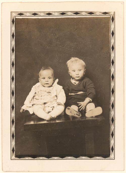 Two infants seated on table, diamond border