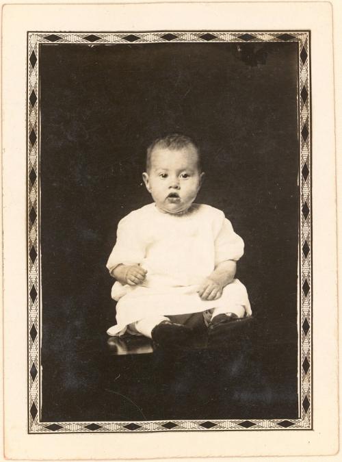 Infant seated on table, diamond border