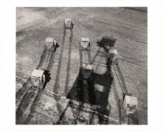 Harvesters with shadow of derrick