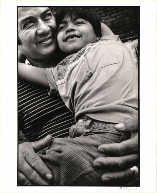 [Son hanging on to his father’s neck, both smiling, New York]