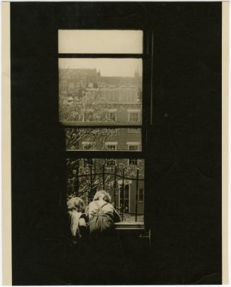 Young children looking down from high rise window with bars