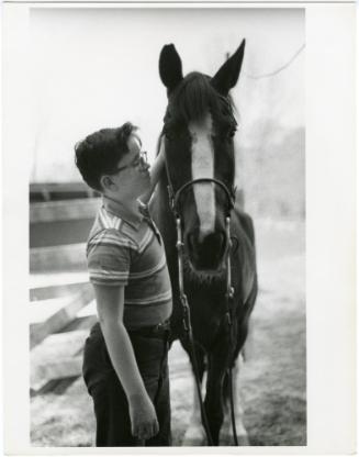 Boy with glasses petting horse outside, from the series Big Brother