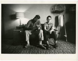 Boy with glasses sitting in living room with father, from the series Big Brother