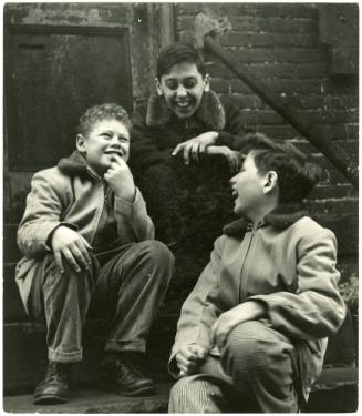 New York City boy laughing with two friends on stoop