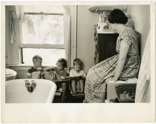 Mother sitting on bathroom counter watching children